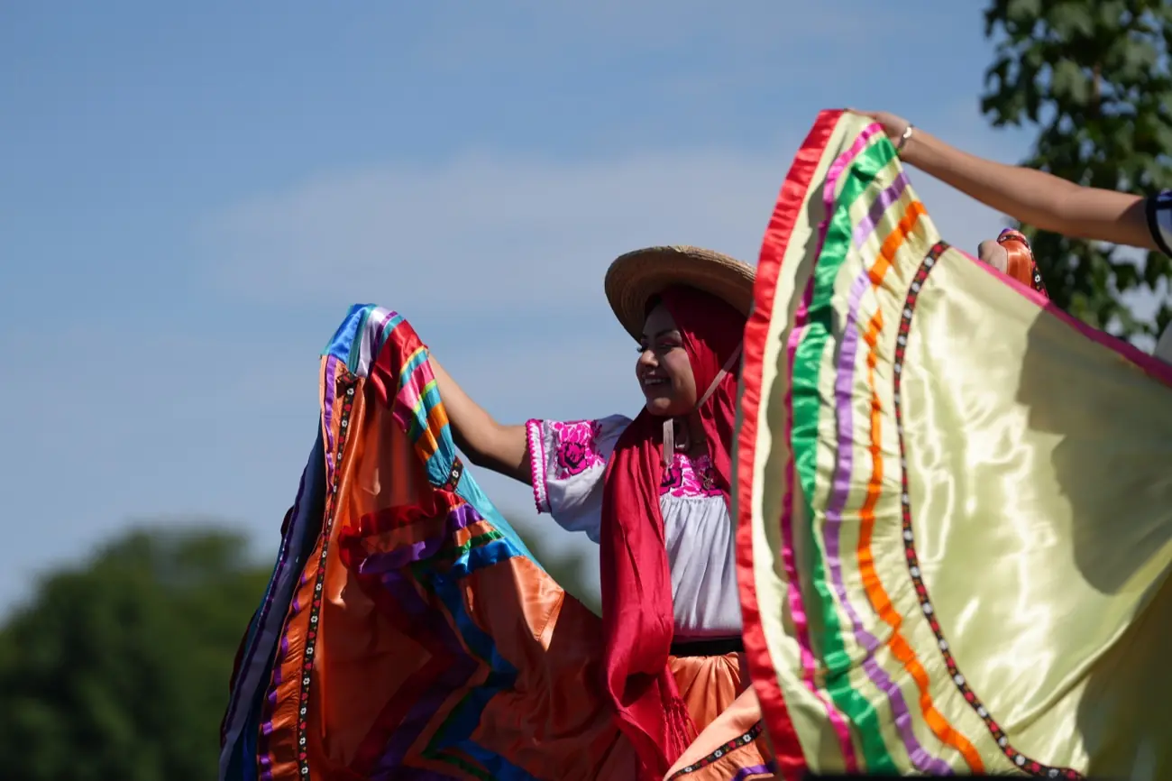 Ballet Folklórico dancers swirling wide skirts of red, green and gold on stage