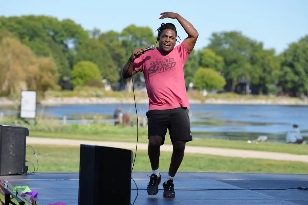 A performer singing on the lakeside stage with Monona Bay behind